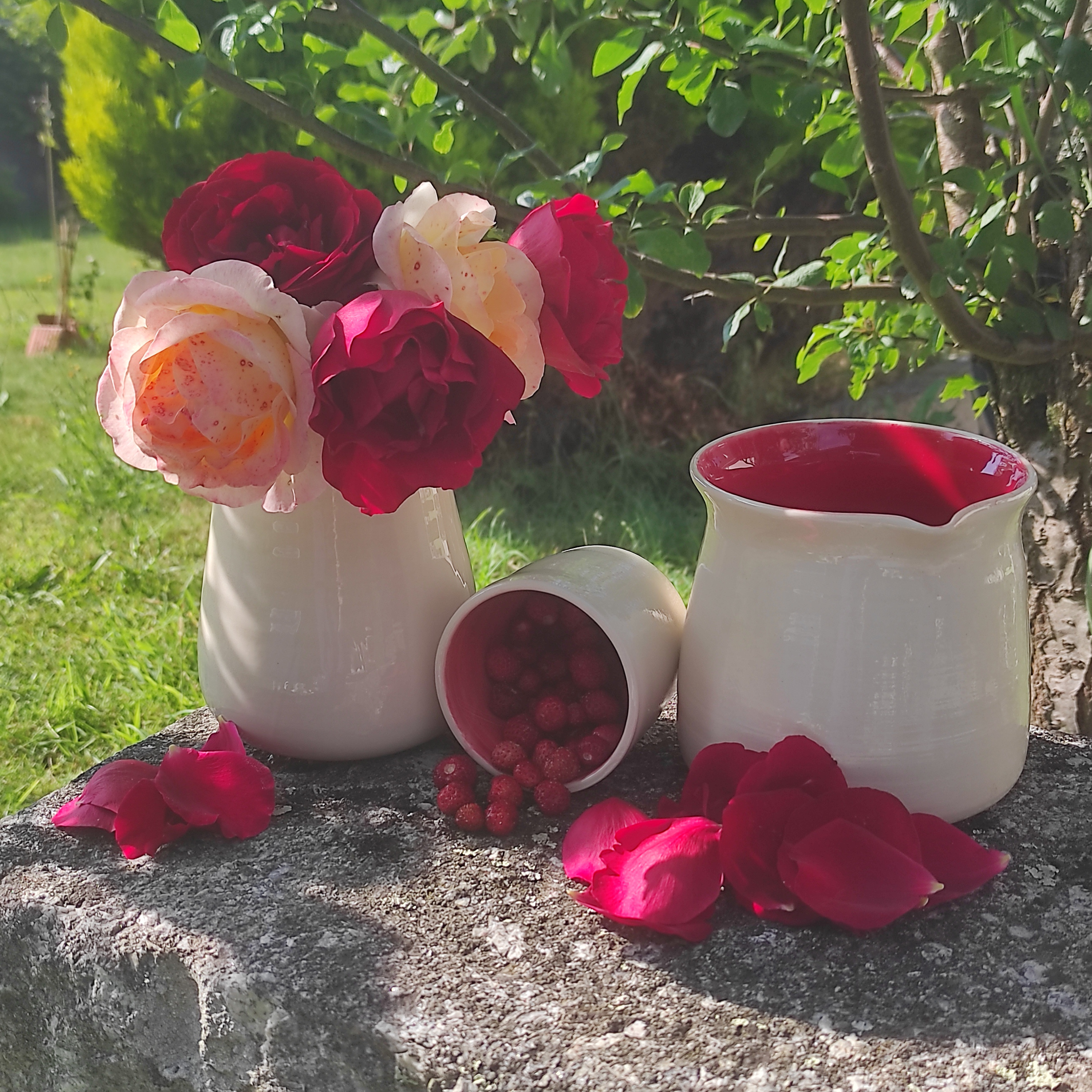 Pichet, gobelet et gobelet rouges avec des fruits et des fleurs rouges également.
